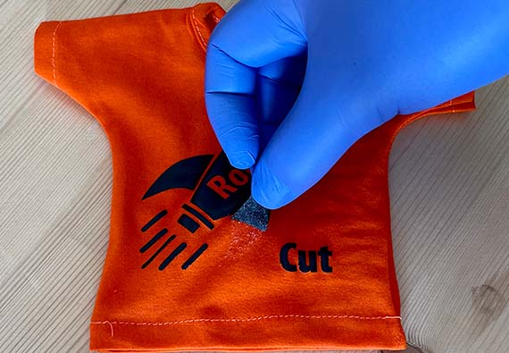 Hånd som drar av folie på oransje t-skjorte